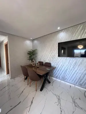 a dining room with a table and a tv on a wall at Le Paradis Balnéaire - 2 min Plage - 2 chambres in Marrakech