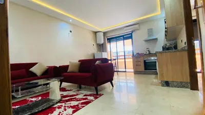 a living room with a red couch and a kitchen at Résidence nour 5 in Marrakech