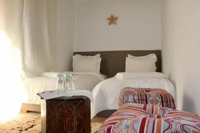 a bedroom with two beds and a table and a chair at La Maison Berber Shams in Marrakech