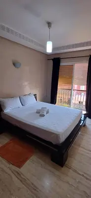 a bedroom with a large bed with white sheets at Résidence hamza appartement 2 chambre in Marrakech