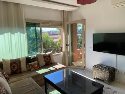 a living room with a couch and a glass table at Appart charmante au cour de marrakech l'hivernage in Marrakech