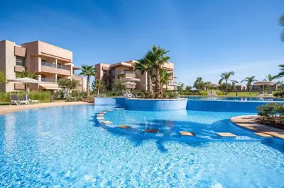 a pool at a resort with palm trees and buildings at Appartement luxueux à Prestigia SAPHIR in Marrakech