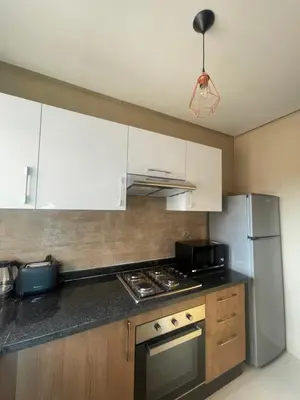 a kitchen with white cabinets and a stainless steel refrigerator at Appartement luxueux à Prestigia SAPHIR in Marrakech