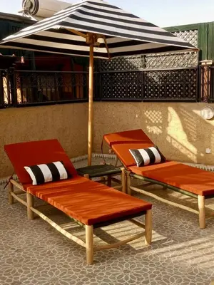 two lounge chairs and an umbrella on a patio at Charmant Riad privatif au cœur de la Médina in Marrakech