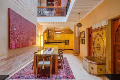 a living room with a table and a kitchen at Charmant Riad privatif au cœur de la Médina in Marrakech