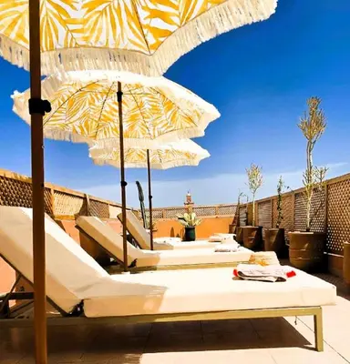 a patio with umbrellas and lounge chairs on a roof at Riad Vilamoura & SPA in Marrakech