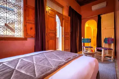 a bedroom with a bed and a window and a chair at Riad Vilamoura & SPA in Marrakech
