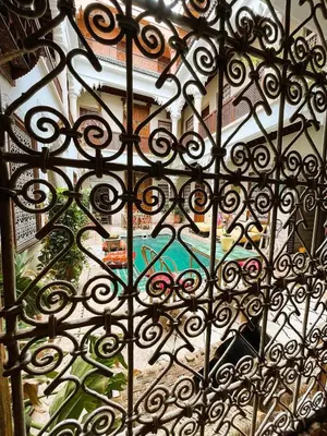an iron gate with a view of a pool at Riad Vilamoura & SPA in Marrakech
