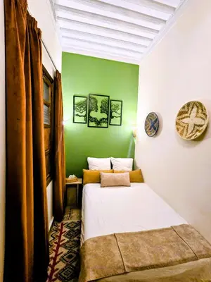 a bedroom with two beds and a green wall at Riad Vilamoura & SPA in Marrakech