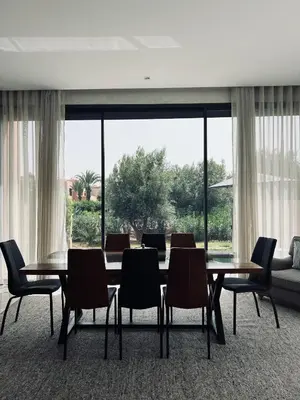 a dining room with a table and chairs and a large window at Dream villa in Marrakech