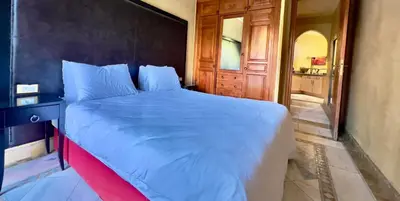 a bedroom with a large bed with a wooden headboard at Palmeraie vue piscine 3 in Marrakech