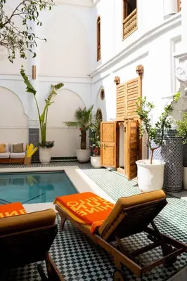 a patio with a pool and two chairs and a swimming pool at Riad Tamazigh in Marrakech