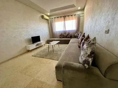 a living room with a couch and a tv at Appartement 2 chambres salon à coté de la gare centre de guéliz 21 in Marrakech