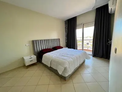 a bedroom with a bed and a large window at Appartement 2 chambres salon à coté de la gare centre de guéliz 21 in Marrakech