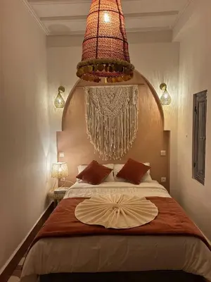 a bedroom with a bed with a large chandelier above it at Riad Be Colors in Marrakech