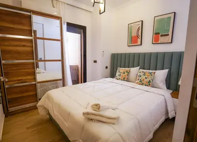 a bedroom with a large white bed and a mirror at Charmant appartement in Marrakech