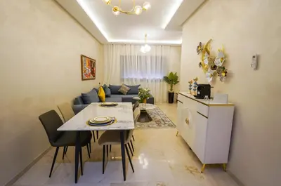 a kitchen and living room with a table and a couch at Charmant appartement in Marrakech