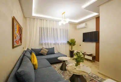 a living room with a blue couch and a tv at Charmant appartement in Marrakech