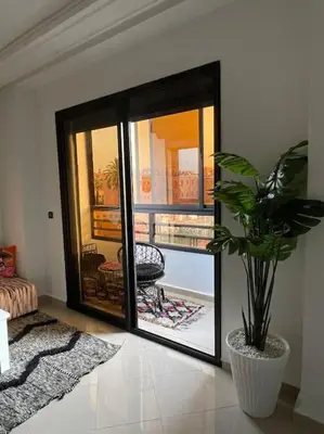 a living room with a potted plant and a glass door at Superbe studio en plein centre in Marrakech