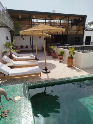 a swimming pool with a umbrella and lounge chairs and a swimming pool at Riad Les Trois Mages in Marrakech