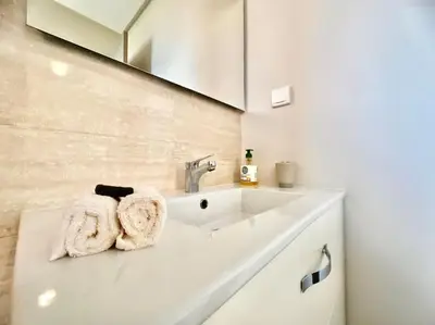 a white bathroom with a sink and a mirror at Appartement Spacieux et Moderne avec une Vue sur Montagne et Piscine in Marrakech
