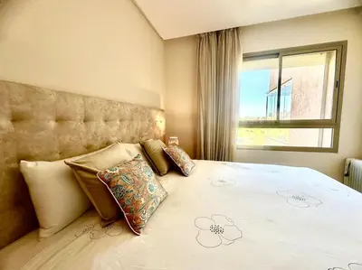 a bedroom with a large bed with pillows and a window at Appartement Spacieux et Moderne avec une Vue sur Montagne et Piscine in Marrakech