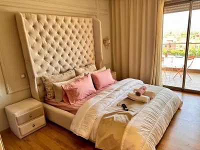 a large bed with pink pillows and a large headboard at Appartement Luxueux avec Piscine 10 minutes du centre ville in Marrakech