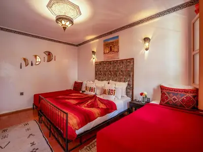 a bedroom with two beds with red sheets at Riad Nakhla in Marrakech