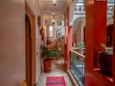a hallway with red walls and a staircase with a plant at Riad Nakhla in Marrakech