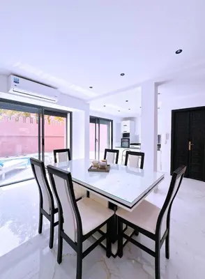 a dining room with a white table and chairs at Villa Jassmin, piscine, à 6km du centre ville in Marrakech