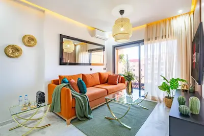 a living room with an orange couch and a glass table at Starlight Studio in Marrakech