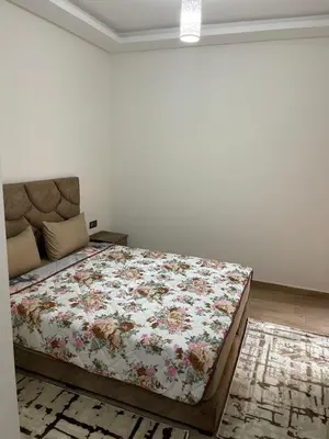 a bedroom with a bed with a floral quilt at Appartement à louer Marrakech in Marrakech