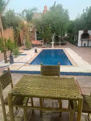 a table and chairs in front of a swimming pool at Maison coco in Marrakech