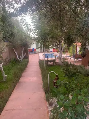 a sidewalk in a park with a bench and trees at Maison coco in Marrakech