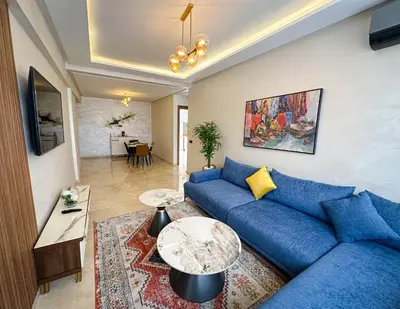a living room with a blue couch and a table at Grand appartement moderne in Marrakech