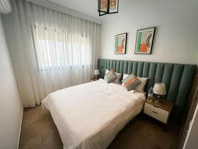 a bedroom with a bed with a green headboard at Grand appartement moderne in Marrakech