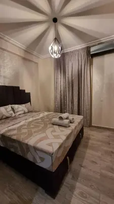 a bedroom with a large bed and a chandelier at Appartement Mima Marrakech Proche centre ville, cosy et spacieux in Marrakech