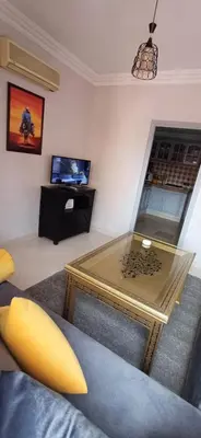 a living room with a glass table and a tv at Résidence Nadia 3 étage appartement 22 in Marrakech