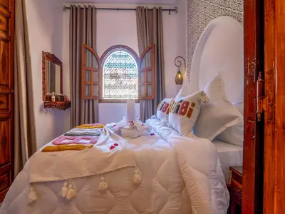 a bedroom with a large bed with white blankets and pillows at Belle Riad de médina in Marrakech