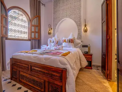 a bedroom with a large bed with a wooden dresser at Belle Riad de médina in Marrakech