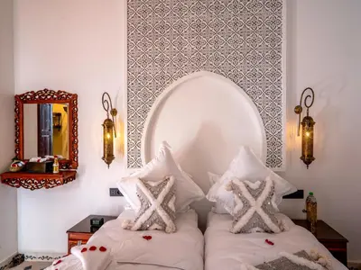 a bedroom with a bed with pillows and a mirror at Belle Riad de médina in Marrakech