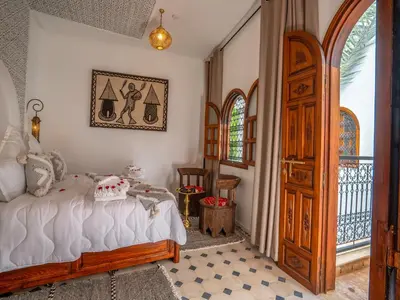 a bedroom with a bed and a large window at Belle Riad de médina in Marrakech