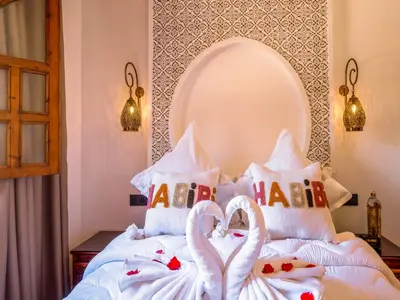 a bed with two swans made out of pillows at Belle Riad de médina in Marrakech