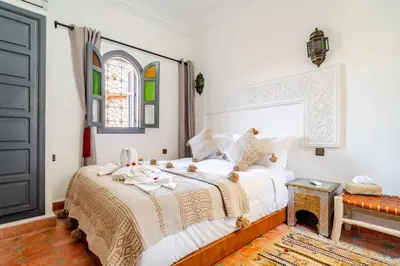a bedroom with a bed with white sheets and a window at Riad La Kasbah secrète - Piscine intérieure in Marrakech