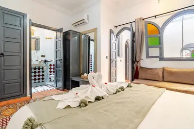 a bedroom with a large bed with white clothes on it at Riad La Kasbah secrète - Piscine intérieure in Marrakech