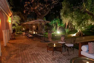 a patio with tables and chairs and an umbrella at Villa Riad luxe centre marrakech majorelle Rue Yves st laurent in Marrakech