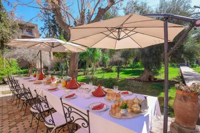 a long table with chairs and an umbrella at Villa Riad luxe centre marrakech majorelle Rue Yves st laurent in Marrakech