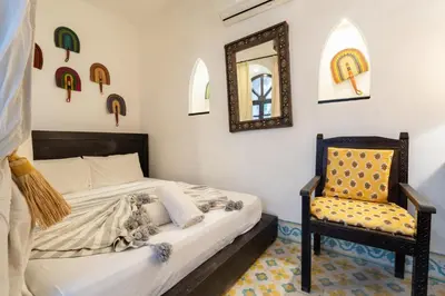 a bedroom with a bed and a chair and a mirror at Riad Sharqi Luminous A Sunny in Marrakech Old Town in Marrakech