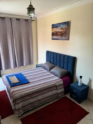 a bedroom with a bed with a blue head board at Charmant Appartement à Gueliz - À Deux Pas des Attractions Locales in Marrakech