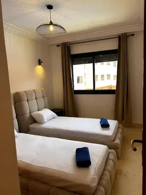 two beds in a hotel room with blue towels on them at Charmant Appartement à Gueliz in Marrakech